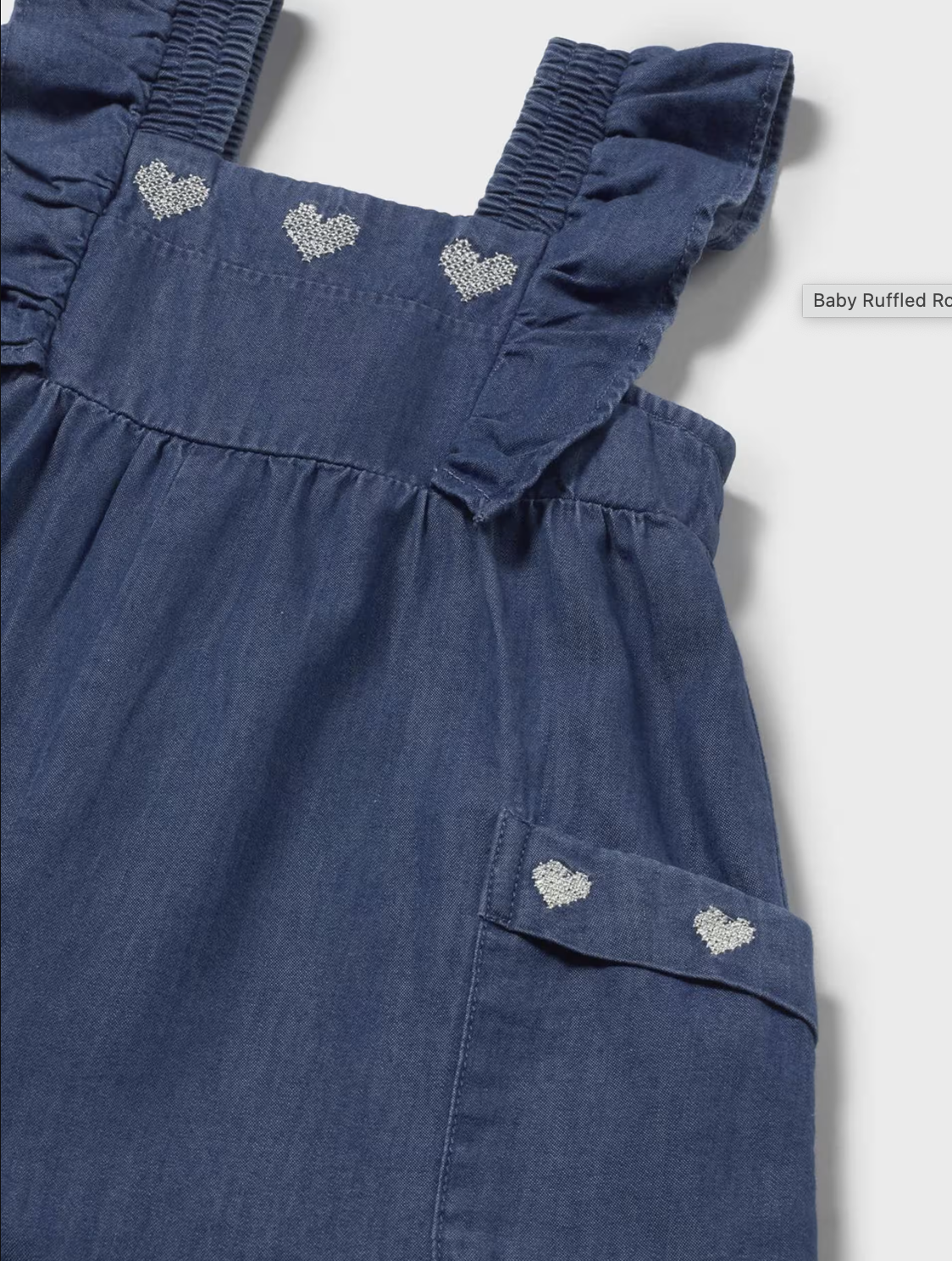 Blue denim romper with ruffled straps on a white background